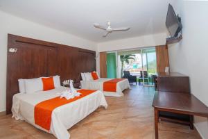 a hotel room with two beds and a flat screen tv at Princess Mayev in Santa Cruz Huatulco