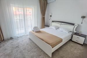 a bedroom with a large white bed and a window at Vila Kalliopi in Eforie Nord