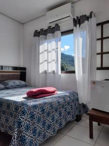um quarto com uma cama e uma janela em Suítes em Ubatuba em Ubatuba