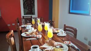 a wooden table with plates of food and glasses of orange juice at Hostal El Pinzón in Puerto Ayora