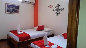 a small room with two beds and a mirror at Hostal El Pinzón in Puerto Ayora