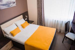 a bedroom with a bed with orange and white pillows at Hotel People in Cheboksary