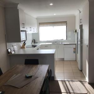 a kitchen with a wooden table and a kitchen with a refrigerator at The Peninsular Merimbula in Merimbula +20 photos