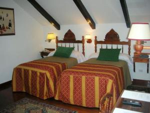 1 dormitorio con 2 camas con mantas verdes y naranjas en Hotel El Relicario Del Carmen en Quito