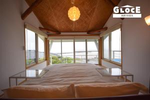 Cama grande en habitación con ventanas en GLOCE 葉山 Ocean View House 都心から1時間 湘南の絶景を独り占めペットok 出張BBQ有り, en Yokosuka