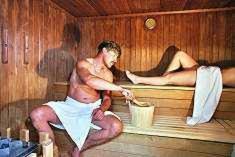 un homme dans un sauna avec une femme assise sur un lit dans l'établissement Hotel Lahnblick, à Bad Laasphe