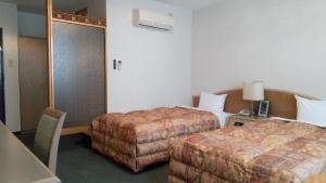 a hotel room with two beds and a ottoman at Leo Plaza Hotel in Sasebo