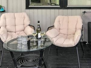 2 Stühle und ein Glastisch mit Weinflaschen und Gläsern in der Unterkunft 6 person holiday home in Nordborg in Nordborg
