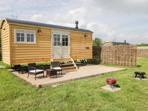 a wooden tiny house with chairs and a patio at Waylands in Faringdon