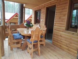 a wooden table and chairs on a porch of a cabin at Domek Shrek in Boszkowo