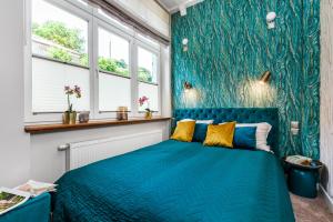 una camera con letto blu in una stanza con finestre di Apartamenty4you - SleepWell Apartment a Sopot