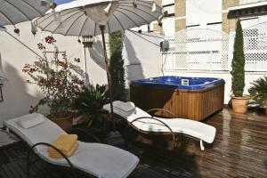 un patio con bañera de hidromasaje, 2 sillas y sombrilla en Alcoba del Rey de Sevilla, en Sevilla