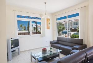 a living room with a couch and a tv at Villa Dafnis Chrysos - Modern 3 Bedroom Protaras Villa with Pool - Close to Fig Tree Bay Beach in Protaras