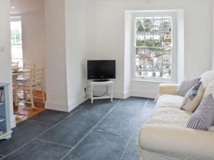 a living room with a couch and a flat screen tv at Rose Cottage in St Austell