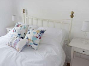 a white bed with two pillows on it with a table at Rose Cottage in St Austell