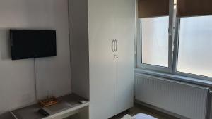 a room with a tv on the wall and a window at Pensiunea Elmo in Constanţa