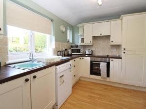a kitchen with white cabinets and a window at 2 Mellfell View in Penrith