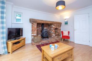 a living room with a brick fireplace and a tv at Bryony Cottage in Aldeburgh
