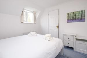a white bedroom with a white bed and a sink at Bryony Cottage in Aldeburgh