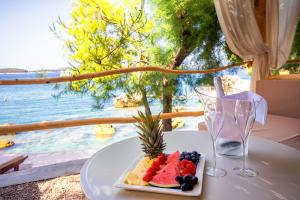 a plate of fruit on a table with a view of the ocean at Hotel Podstine in Hvar