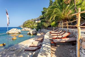 a row of chaise lounge chairs on a beach at Hotel Podstine in Hvar