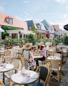 zwei Frauen sitzen an Tischen in einem Restaurant im Freien in der Unterkunft La suite new-yorkaise Disneyland Paris in Serris