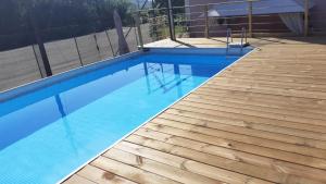 a blue swimming pool with a wooden deck at B&B Il Tempo Del Vento-Camere e Appartamenti in Tresana