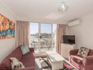 Una sala de estar con un sofá y un televisor. en Horizons 213/10 Kosciuszko Road, en Jindabyne