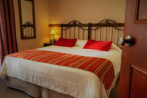 1 dormitorio con 1 cama grande con almohadas rojas en Don Pepe Hotel y Cabañas en El Calafate
