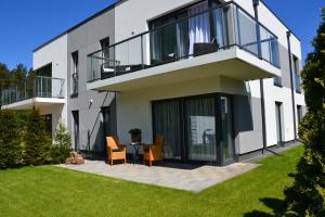 a large white house with a lawn in front of it at Luksusowe Apartamenty Bursztynowy Las ,,Leśny Poranek'' z ogrodem i widokiem na las Ustka in Ustka