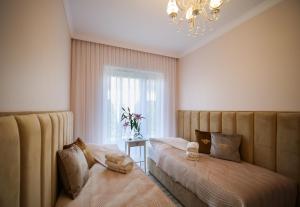 um quarto com 2 camas e um lustre em Luksusowe Apartamenty Bursztynowy Las ,,Leśny Poranek'' z ogrodem i widokiem na las Ustka em Ustka