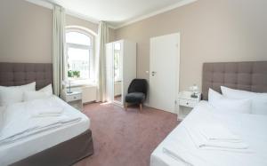 um quarto com 2 camas, uma cadeira e uma janela em Appartementhaus Zum Strandkorb em Kühlungsborn