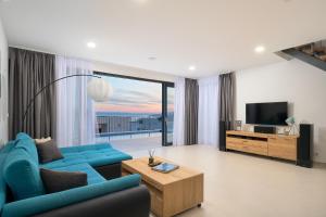 a living room with a blue couch and a television at Villa Maxima with heated pool - Makarska Veliko Brdo in Makarska