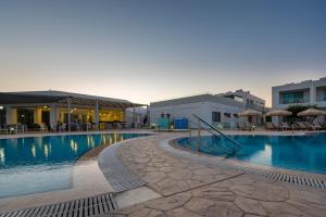 basen ze stołami i parasolami obok budynków w obiekcie Royal Bay Suites w mieście Kefalos