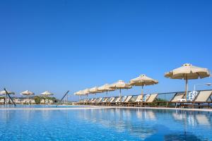 a row of chairs and umbrellas next to a swimming pool at Royal Bay Suites in Kefalos