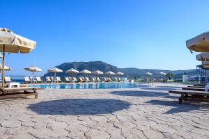 a swimming pool with chairs and umbrellas on a beach at Royal Bay Suites in Kefalos