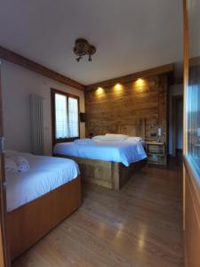 two beds in a room with wooden walls at Hotel Oasi in San Vito di Cadore