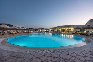 a large swimming pool with chairs and umbrellas at Royal Bay Suites in Kefalos
