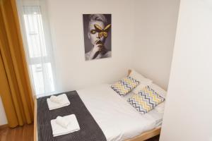 Millenium apartment في سوكو بانيا: غرفة نوم صغيرة بسرير وفوط بيضاء