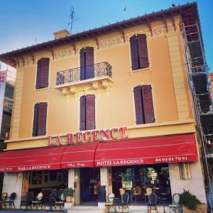 a building with a red awning on a street at Hotel La Regence in Villefranche-sur-Mer