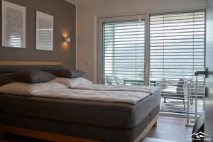 łóżko w pokoju z dużym oknem w obiekcie Top 19 Alpe Maritima - Luxury Lakeview Apartment w mieście Annenheim