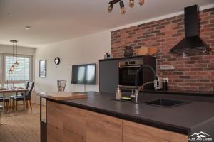 a kitchen with a black counter top and a brick wall at Top 19 Alpe Maritima - Luxury Lakeview Apartment in Annenheim