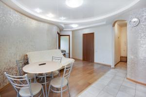 ハバロフスクにあるАппартаменты на Истомина, 41のテーブルと椅子、壁に時計が備わる客室です。
