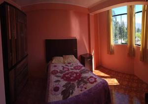 1 dormitorio con 1 cama con colcha de flores y ventana en La Azotea, en Huancayo