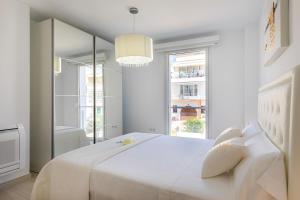 a white bedroom with a large white bed and a mirror at MEVAMAR in Fornells