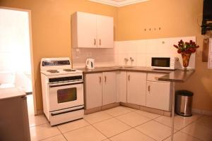 una cocina con electrodomésticos blancos y armarios blancos en Chancellors Court Guest House en Pretoria