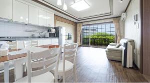 a kitchen with white cabinets and a table and chairs at Jeju Time-Travel Pension in Jeju