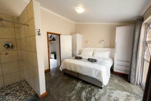 a bedroom with a large bed and a shower at Treyntjes Rivier Cottages in Caledon