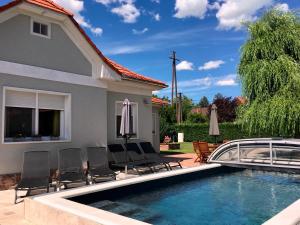 a pool with chairs and umbrellas next to a house at Vento Balaton in Alsóörs