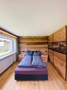 Bett in einem Zimmer mit einer Holzwand in der Unterkunft Kitz Kaiser Appartement in Sankt Johann in Tirol
